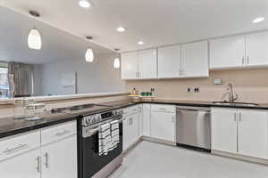 Kitchen featuring stainless steel appliances, decorative light fixtures, white cabinets, light tile patterned floors, and decorative backsplash