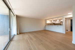 Unfurnished living room featuring light wood-style floors and baseboards