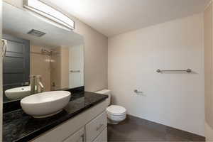Bathroom featuring vanity, a shower, dark tile patterned floors, and a textured ceiling