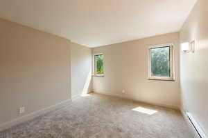 Spare room with a baseboard heating unit and carpet floors
