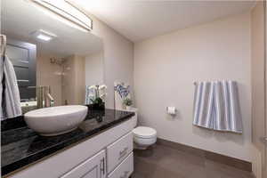 Bathroom with vanity, dark tile patterned flooring, and a shower