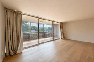 Unfurnished room with a wall of windows and light wood-style flooring