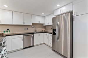 Kitchen featuring appliances with stainless steel finishes, white cabinetry, recessed lighting, and light tile patterned flooring