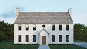 View of front of house featuring a chimney, a front lawn, and brick siding