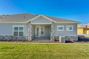 Craftsman-style home with stone siding, a shingled roof, and a front lawn