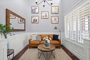 Sitting room with a chandelier, wood finished floors, a decorative wall, and wainscoting
