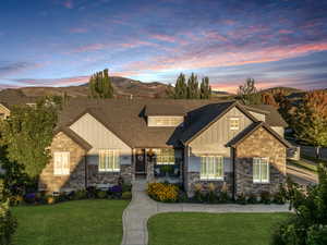 Craftsman-style home featuring board and batten siding, roof with shingles, a lawn, and a mountain view