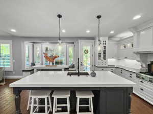Kitchen featuring pendant lighting, dark wood-style floors, recessed lighting, white cabinetry, and a kitchen breakfast bar