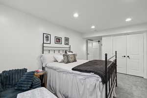 Carpeted bedroom with a barn door, recessed lighting, and a closet