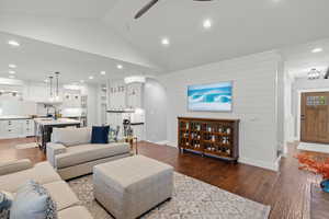 Living room featuring recessed lighting, dark wood-style flooring, vaulted ceiling, a ceiling fan, and wood walls