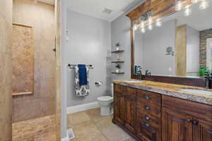 Full bath featuring double vanity, a walk in shower, and light tile patterned floors