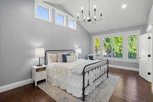 Bedroom with dark wood-type flooring, high vaulted ceiling, and a chandelier