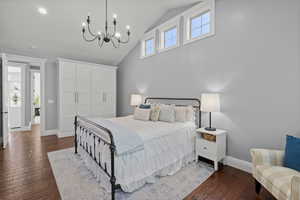 Bedroom with dark wood-style floors, high vaulted ceiling, and a chandelier