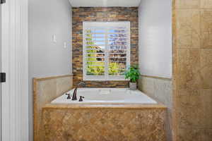 Full bath featuring a bath and tile walls