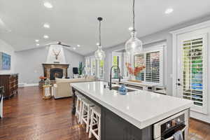 Kitchen with recessed lighting, a fireplace, pendant lighting, dark wood-style floors, and vaulted ceiling