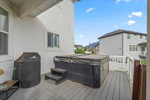 Wooden deck featuring a hot tub, area for grilling, and a residential view
