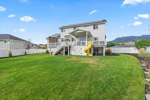 Rear view of property with stairs, a fenced backyard, roof mounted solar panels, a deck with mountain view, and a patio