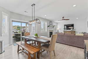 Dining area with a stone fireplace, plenty of natural light, light wood-style flooring, and recessed lighting