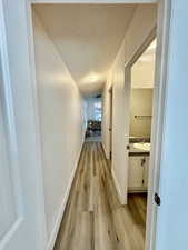 Corridor featuring a textured ceiling and light wood-style flooring