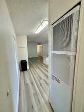 Hall featuring a heating unit, light wood-type flooring, and a textured ceiling