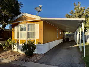 View of property exterior featuring a carport and asphalt driveway