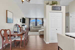 Dining area featuring dark wood-style flooring and lofted ceiling
