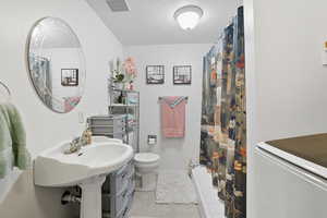 Full bath light tile patterned flooring, a tub/shower combo, and washer / clothes dryer