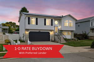 Bi-level home featuring solar panels, driveway, and an attached garage