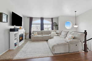 Living room, plenty of natural light, wood finished floors, and lofted ceiling
