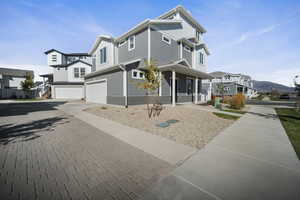 View of front of property with an attached garage, decorative driveway, covered porch, a residential view, and a mountain view