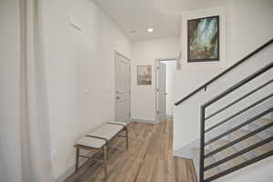 Foyer featuring light wood finished floors, stairway, and recessed lighting