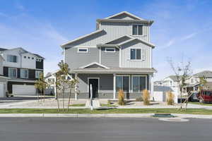 View of front of home with board and batten siding, covered porch, a residential view, and a front lawn
