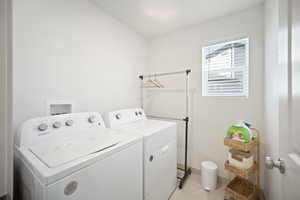 Washroom with separate washer and dryer and light tile patterned floors