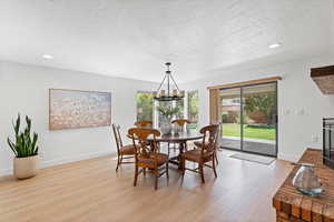 Dining space with recessed lighting, light wood finished floors, healthy amount of natural light, a textured ceiling, and a chandelier