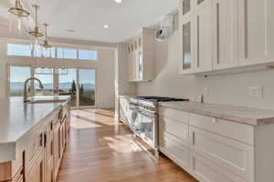 Kitchen with a mountain view, double oven range, glass insert cabinets, decorative light fixtures, and light wood-type flooring