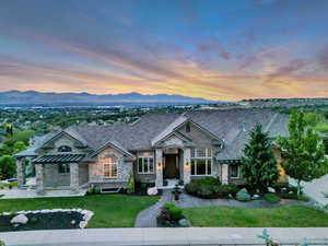 View of front of house featuring stone siding, a front yard, and a mountain view