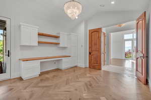 Unfurnished office featuring built in desk, a chandelier, lofted ceiling, and recessed lighting