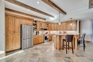 Kitchen featuring a kitchen breakfast bar, glass insert cabinets, stainless steel appliances, open shelves, and recessed lighting