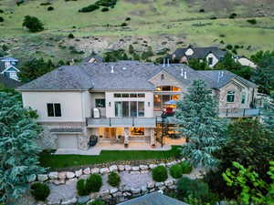 Back of house with a patio area, stucco siding, stone siding, stairs, and a balcony