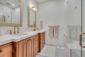 Full bathroom with decorative backsplash, a stall shower, light tile patterned floors, and double vanity