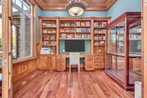 Office with healthy amount of natural light, built in study area, light wood-type flooring, and crown molding