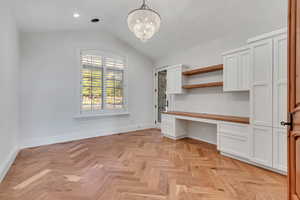 Unfurnished office featuring built in study area, a chandelier, vaulted ceiling, and recessed lighting