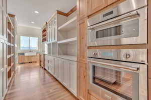 Kitchen featuring light brown cabinets, light wood-style floors, recessed lighting, stainless steel double oven, and open shelves