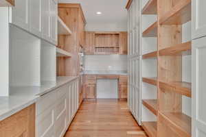Kitchen featuring light wood-style flooring, recessed lighting, light brown cabinetry, and double oven