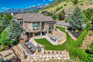 Back of property with a patio, stone siding, an outbuilding, an outdoor fire pit, and a yard