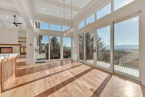 Unfurnished sunroom with beamed ceiling, a mountain view, plenty of natural light, and a chandelier
