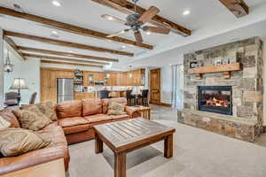 Living area featuring beam ceiling, a fireplace, a ceiling fan, recessed lighting, and light carpet