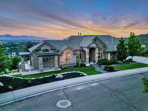 French provincial home with stone siding, a front lawn, and a mountain view