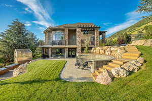 Rear view of property with a balcony, an exterior structure, stairs, a patio area, and an outbuilding
