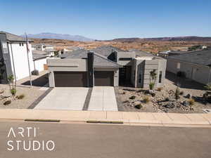 View of front of house featuring a garage, stucco siding, driveway, a mountain view, and a residential view